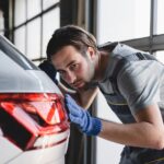 Mechanic checking car paint repairing fixing after scratches at vehicle inspection service MOT.
